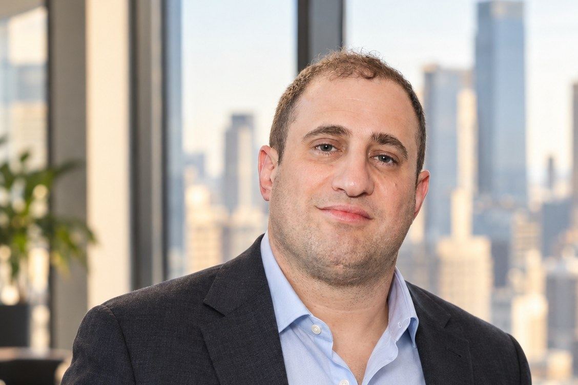 Michael Stern standing by a window with the city behind him