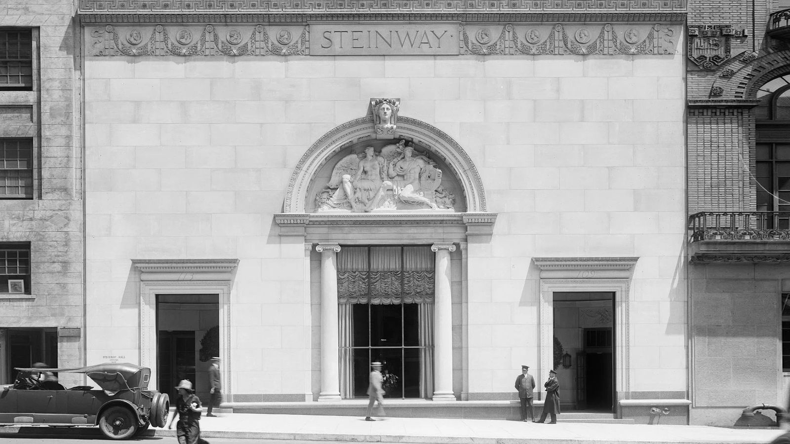 An archival photograph of the Steinway Hall facade, its carved pediment and arched entrance.