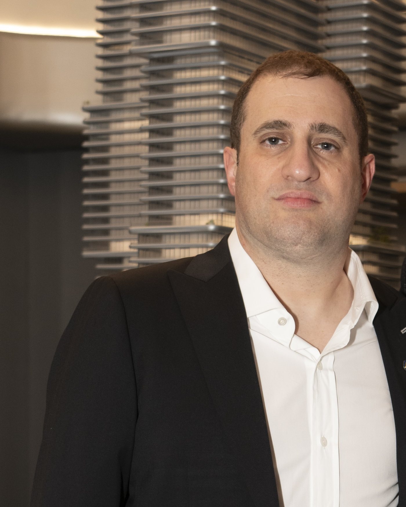 Michael Stern stands in front of an architectural scale model of a stepped tower.