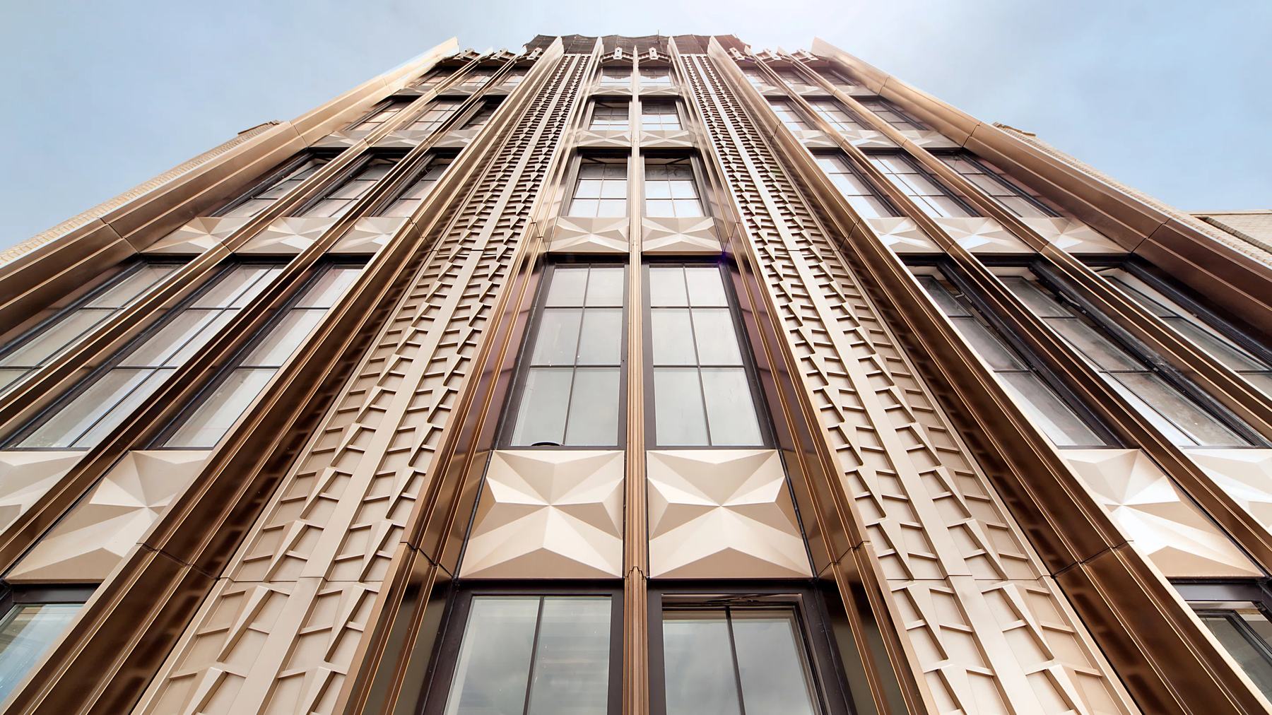 Looking straight up the facade, brick piers and patterned spandrels run to the top of the frame.